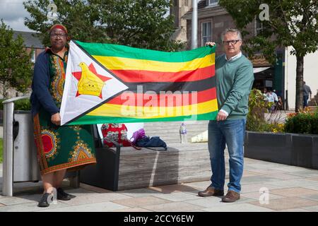 Les manifestants au Zimbabwe sont des sujets de protestation à Helensburgh, avec des pancartes et un drapeau, en soutien à Harriet Ndlovu, y compris le député Brendan O'Hara. Banque D'Images