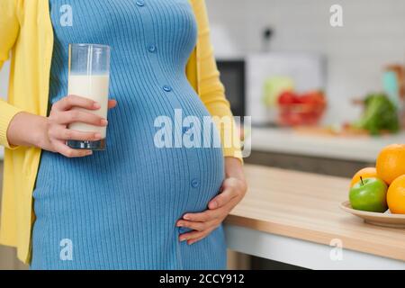 Jeune femme enceinte avec un verre de lait en cuisine Banque D'Images