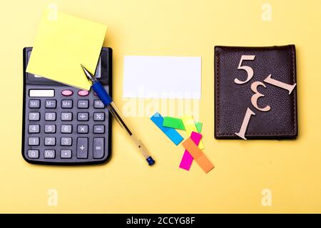 Carte de visite, signets et pense-bête. Papeterie, portefeuille avec chiffres et calculatrice. Concept de fournitures de bureau et de finances. Jeu de papiers notes jaunes, calculatrice et stylo sur fond jaune. Banque D'Images