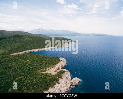 Bord de mer des Rocheuses près du camping Veslo au Monténégro. Bleu azur, vagues blanches qui frappent les rochers, jour d'été ensoleillé, vue aérienne sur les drones. Banque D'Images