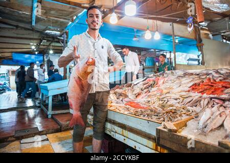 vendeur de poisson égyptien montrant de grands poissons frais du comptoir en arrière-plan du marché de rue Banque D'Images