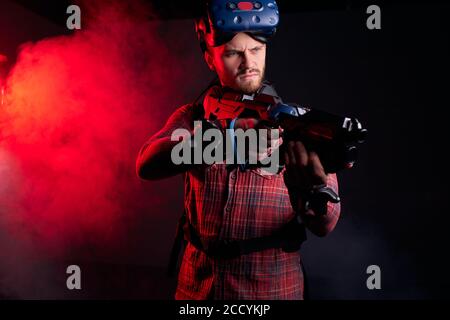 Portrait d'un homme debout en studio, fond noir, rayons ultraviolets réfléchis sur l'homme. Tenir une arme spéciale Banque D'Images