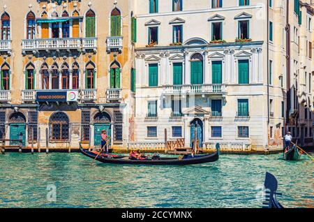Venise, Italie, 13 septembre 2019 : gondolier et touristes en gondole bateau traditionnel naviguant sur l'eau du Grand Canal avec architecture vénitienne typique bâtiments colorés arrière-plan Banque D'Images