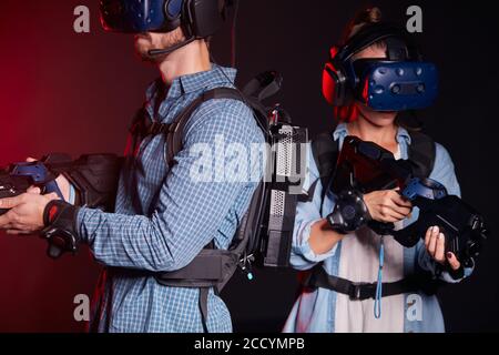 fille et garçon dans les pousses de lunettes virtuelles et avec virtuel armes isolées sur fond de lumière néon Banque D'Images