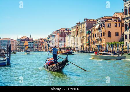Venise, Italie, 13 septembre 2019 : gondolier et touristes en gondole bateau traditionnel naviguant sur l'eau du Grand Canal avec architecture vénitienne typique bâtiments colorés arrière-plan Banque D'Images