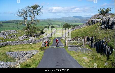 Cycliste sur une voie tranquille au-dessus de Ribblesdale, parc national de Yorkshire Dales, Royaume-Uni. Banque D'Images