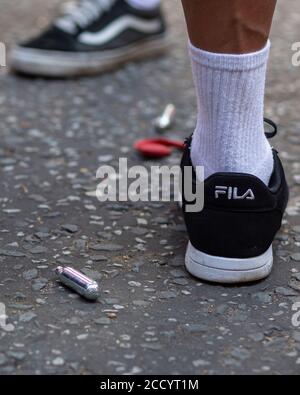 Vue des pieds d'un peuple se tenant à côté des bidons d'oxyde nitreux rejetés sur une route pendant le carnaval de Notting Hill, Londres, 2019 Banque D'Images