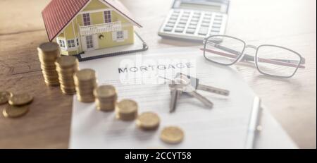 Contrat hypothécaire pour l'achat ou la vente d'une maison d'appartement ou d'un immeuble. Bureau de travail avec calculatrice et stylo maison à pièces contractuelles Banque D'Images