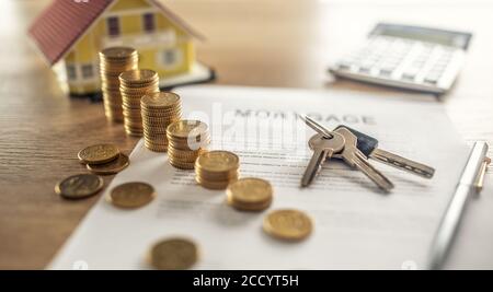 Contrat hypothécaire pour l'achat ou la vente d'une maison d'appartement ou d'un immeuble. Bureau de travail avec calculatrice et stylo maison à pièces contractuelles Banque D'Images