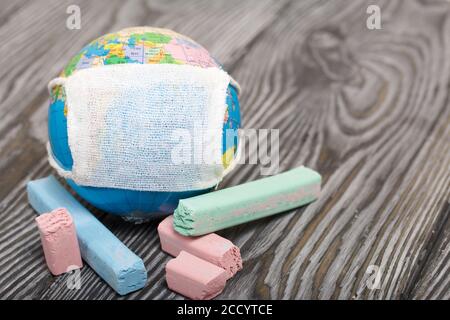 Globe avec masque médical. À proximité sont des crayons. Année académique pendant l'épidémie. Banque D'Images