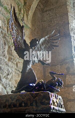 St Michael lance Lucifer dans une sculpture en bronze dans la chapelle du mont St Michaels, en Cornouailles. La lumière d'une fenêtre en vitraux à proximité ajoute une touche dramatique. SC Banque D'Images