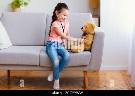 Enfant asiatique fille jouant docteur traitant jouet ours à la maison Banque D'Images