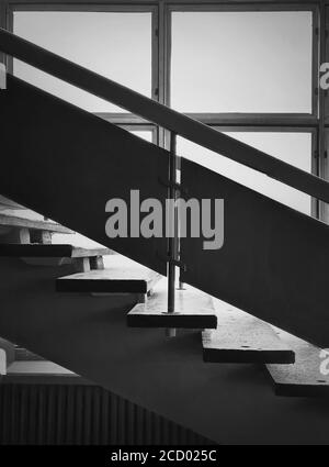 Détails de l'architecture intérieure en noir et blanc, vieux escalier près de la fenêtre. Balustrades en bois et marches d'escalier en pierre à l'intérieur d'un bâtiment miteux. Constante Banque D'Images