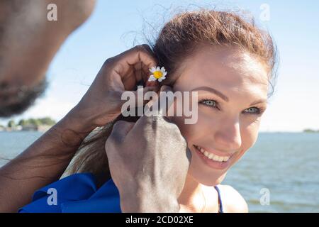 Un homme africain et une femme européenne de race blanche pour une promenade, UN homme insère une fleur dans ses cheveux. Gros plan rogné jour d'été. Photo de haute qualité Banque D'Images