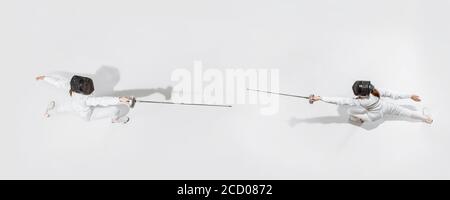 D'abord. Jeune fille en costume d'escrime avec épée à la main sur fond blanc. Vue de dessus. Jeune femme modèle pratique et formation en mouvement, action. CopySpace. Sport, jeunesse, mode de vie sain. Collage. Banque D'Images