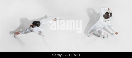 D'abord. Jeune fille en costume d'escrime avec épée à la main sur fond blanc. Vue de dessus. Jeune femme modèle pratique et formation en mouvement, action. CopySpace. Sport, jeunesse, mode de vie sain. Collage. Banque D'Images