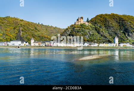 Vue ensoleillée sur le village Sankt Goarshausen avec des maisons blanches sur le Rhin en Allemagne et un château sur une colline au-dessus du village. Banque D'Images