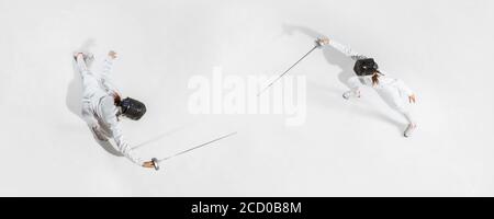 D'abord. Jeune fille en costume d'escrime avec épée à la main sur fond blanc. Vue de dessus. Jeune femme modèle pratique et formation en mouvement, action. CopySpace. Sport, jeunesse, mode de vie sain. Collage. Banque D'Images