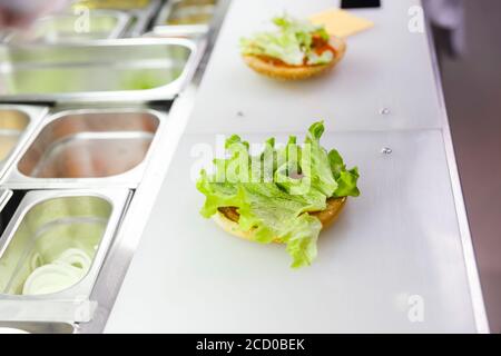 Faire cuire en ajoutant la laitue sur le hamburger. Préparation du hamburger au restaurant. Banque D'Images