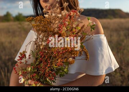 portrait rapproché d'une fille, avec un bouquet de fleurs sauvages dans ses mains. Dans le champ. Femme tenant un bouquet de fleurs lupin bleues Banque D'Images