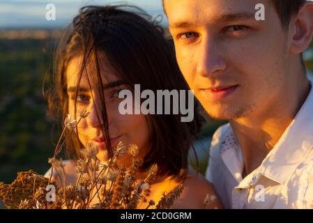 gros plan portrait d'un gars avec une fille, sur fond de soleil couchant, soirée d'été. un gars avec une fille, un jeune couple de vingt-deux ans o Banque D'Images