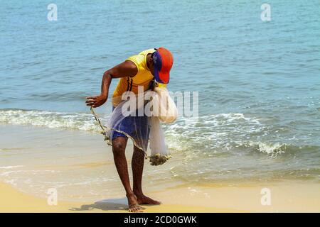 La vie des pêcheurs traditionnels au Kerala, bateau de pêche en bois, pêcheur jetant le filet dans le rivage, pêcheur répare le filet de pêche, Banque D'Images