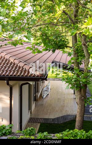 Un fragment d'un toit carrelé d'un bungalow dans les bois et un canoë dans la cour. Banque D'Images