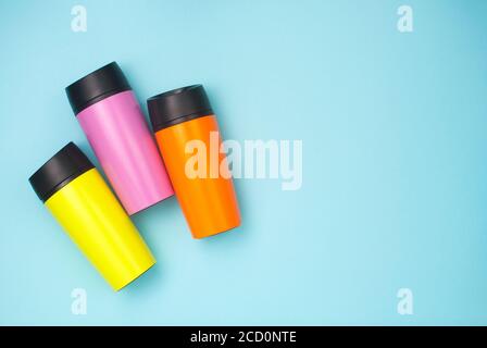 Mugs thermiques multicolores sur fond bleu avec espace vide pour le texte. Vue de dessus, plan d'appartement. Banque D'Images