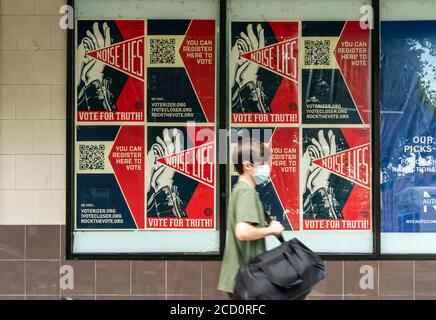 Les piétons marchent devant la publicité pour l'inscription des électeurs le quartier de Chelsea, à New York, le vendredi 14 août 2020. (© Richard B. Levine)