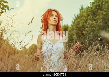 Femme debout dans de l'herbe haute sèche Banque D'Images