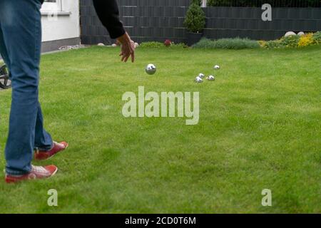 Les boules de boccia en acier chromé reposent sur une surface d'herbe. Femme jouant à la boccia dans le jardin. Banque D'Images