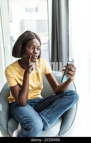 technologie et concept de personnes - souriant femme afro-américaine dedans lunettes avec smartphone à la maison Banque D'Images