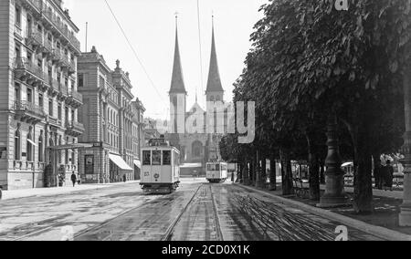 Photographie d'époque en noir et blanc des années 1920, en direction de la cathédrale de Lucerne, en Suisse. Vous pourrez voir des tramways électriques en bas de la rue. Banque D'Images