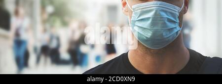 homme portant un masque médical dans une rue urbaine surpeuplée pendant une pandémie de virus Banque D'Images