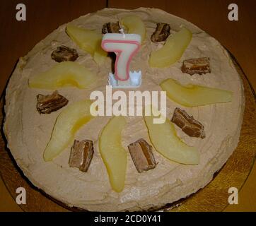 Une barre de chocolat et un gâteau de poire pour le septième anniversaire. Avec le 7 comme bougie. Tranches de poire et barres de chocolat. Banque D'Images