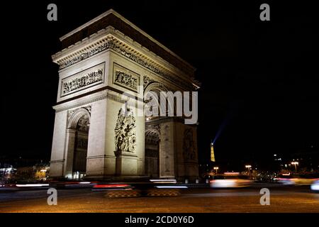 Arc de Triomphe, Paris la nuit - Arc de Triomphe, champs Elysées et Tour Eiffel en arrière-plan avec des voitures en mouvement. Prise de vue en exposition longue Banque D'Images