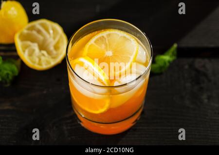 Le thé glacé au citron vert s'approche sur fond sombre. Une boisson rafraîchissante d'été faite de citron frais pressé à la main mélangé avec du thé noir froid, de la glace et de la suga Banque D'Images