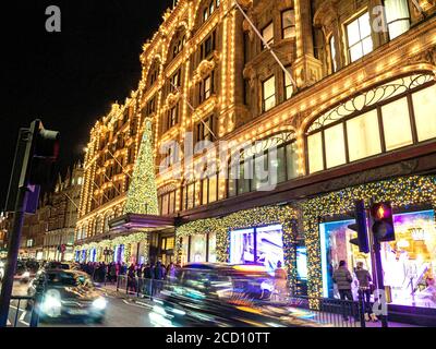 SHOPPING DE NOËL LONDON HARRODS TREE SHOPPERS LONDON Harrods grand magasin au crépuscule avec des foules de shopping de lumières de Noël et de passage de voitures Knightsbridge Londres SW1 Banque D'Images