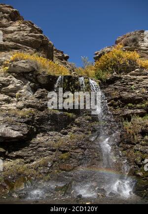 Un arc-en-ciel se forme à cause de minuscules gouttelettes d'eau provenant d'une cascade par un jour ensoleillé. Banque D'Images