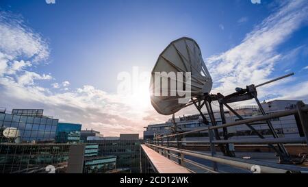 Plat satellite sur un bâtiment de bureau moderne, ciel bleu et coucher de soleil. Concept de communication longue distance Banque D'Images