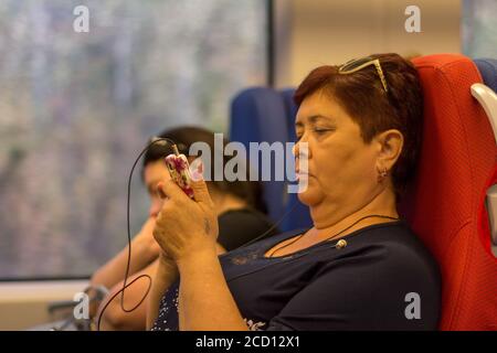 Sotchi, Russie - 21 août 2018 : une femme de soixante ans avec un téléphone mobile se déplace en train à grande vitesse Swallow en été Banque D'Images