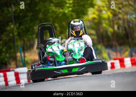 Adulte et enfant dans un casque conduisant le karting sur piste Banque D'Images