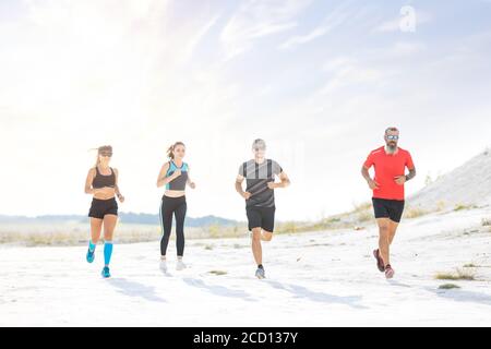 Groupe d'amis qui s'exécutent en plein air le soir. Banque D'Images