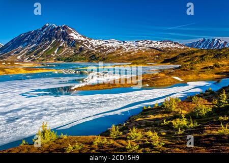 Lac perdu à moitié gelé le matin, montagnes Chugach en arrière-plan.Forêt nationale de Chugach, péninsule de Kenai, centre-sud de l'Alaska au printemps... Banque D'Images