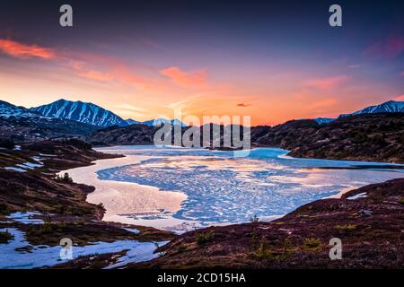 Lac perdu à moitié gelé le soir, montagnes Chugach en arrière-plan. Forêt nationale de Chugach, péninsule de Kenai, centre-sud de l'Alaska au printemps Banque D'Images