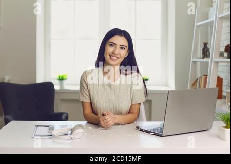 Une femme heureuse avec un ordinateur portable regardant l'appareil photo à l'intérieur. Femme d'affaires travaillant en ligne depuis la maison. Étudiant sur l'apprentissage à distance Banque D'Images
