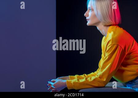 jolie fille pensive ayant un repos, gros plan vue sur le côté photo. femme pensive dans élégant chandail jaune regardant dans la distance, espace de copie Banque D'Images