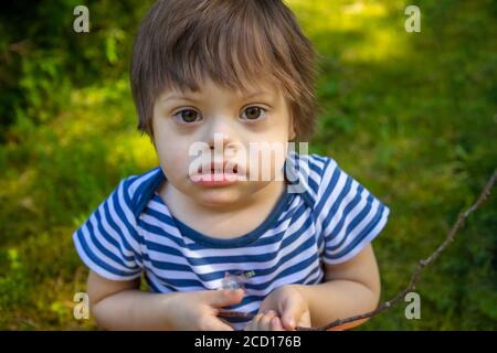 Portrait de bébé garçon avec le syndrome de Down jouant en été jour sur la nature Banque D'Images