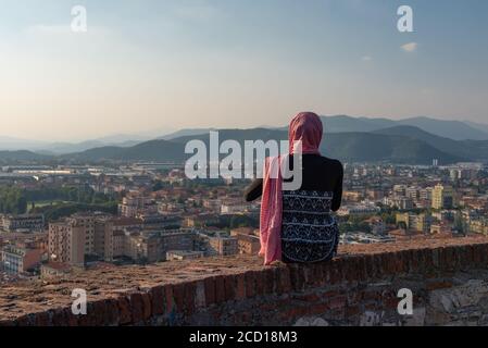 Fille égyptienne avec smartphon sur le toit-terrasse avec vue aérienne de la vieille ville italienne Brescia. Banque D'Images