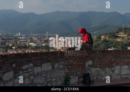 Fille égyptienne avec smartphon sur le toit-terrasse avec vue aérienne de la vieille ville italienne Brescia. Banque D'Images